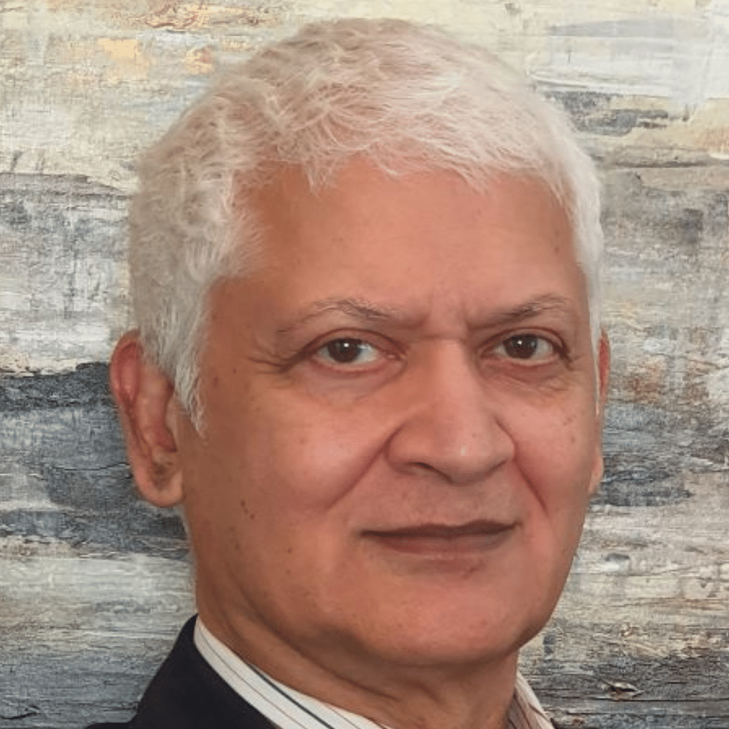 Rajiv Datar in a white collared shirt and black jacket in front of a multi-colored wall