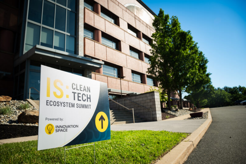 Image has a sign in front of the Innovation Space. The sign shows that the IS:CleanTech Ecosystem Summit is through the building doors.