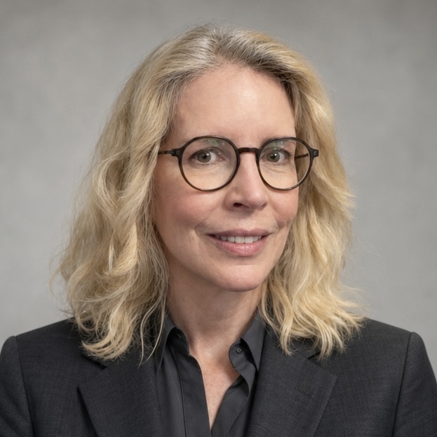 A woman with blonde, curly hair in dark glasses and a black suit jacket.